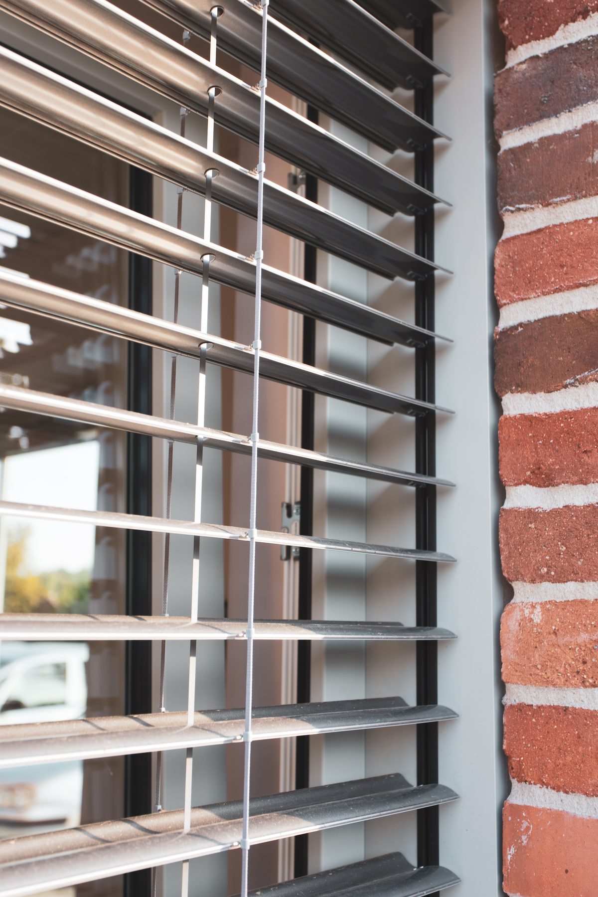 Raffstore mit verstellbaren Aluminium-Lamellen an einer Ziegelfassade